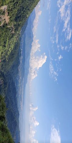 the view from an airplane looking down at water and mountains in the distance with trees on either side