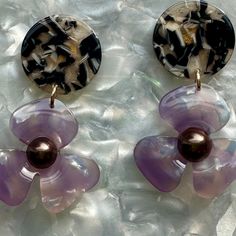 Our three-petal pearl water poppy drop earring is a must-have for any stylish babe. This lightweight, sweet pair features a light purple acrylic flower with a deep brown pearl-studded center, and a contrasting beige and black hand-swirled acrylic stud.   Designed for Closet Rehab. Handmade in Pittsburgh, PA. Made in the USA. Materials: acrylic, brass base posts/jump rings with 18k gold plating Hypoallergenic  Our accessories are handcrafted from colorful acrylic. To preserve your Closet Rehab products, we recommend storing safely in our pouches. Avoid contact with harsh substances like perfumes and hairsprays. Items with plated metals naturally tarnish over time when exposed to body oils and other natural elements. Please handle with care, as excessive dropping, wear and tear, and improper Trendy Purple Flower Earrings For Gift, Purple Acrylic, September Birthstone Jewelry, Acrylic Flower, August Birthstone Jewelry, July Birthstone Jewelry, Mini Hoop Earrings, Beige And Black, Zodiac Jewelry