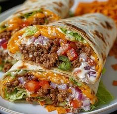 two burritos with meat, cheese and vegetables on a plate