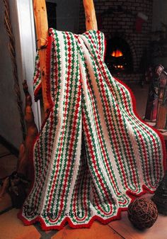 a crocheted blanket sitting on top of a chair next to a fire place