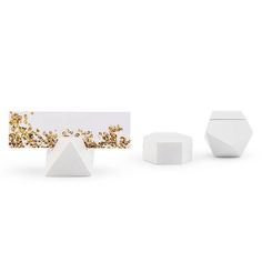 three small white vases with gold sprinkles on them