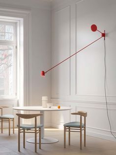 a white table with two chairs and a red lamp on it in front of a window