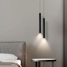 a bedroom with a bed, table and two lights hanging from the ceiling above it