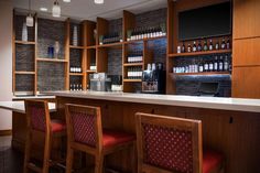 an empty bar with red chairs and bottles on the shelves