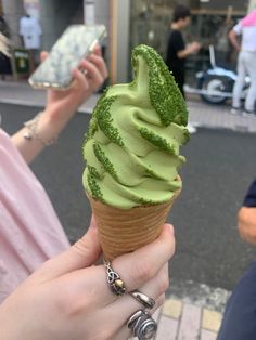 a person holding an ice cream cone with green sprinkles