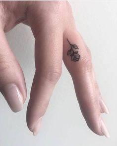 a person's hand with a small flower tattoo on their left thumb and finger