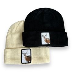 two beanies with deer on them, one is white and the other is black