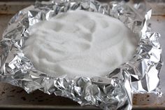 a metal pan filled with white powder on top of a counter covered in tin foil