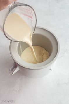 a person pouring milk into a white cup