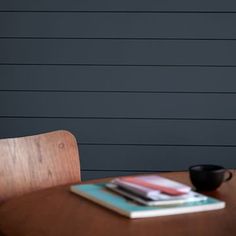 a wooden table topped with a black cup next to a stack of books on top of it