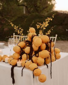 a table topped with lots of yellow fruit and candles next to a white table cloth