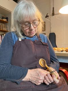 an older woman with glasses holding a wooden spoon