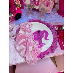 a pink table setting with wine glasses and napkins