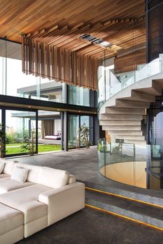 a large white couch sitting in front of a glass wall next to a stair case