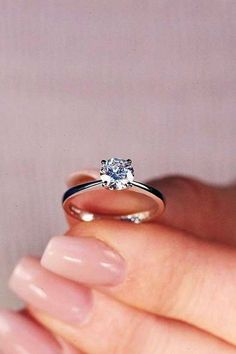 a woman's hand holding an engagement ring with a diamond on the top and bottom