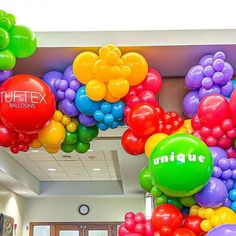 colorful balloons are hanging from the ceiling in an office building that reads, uniquie