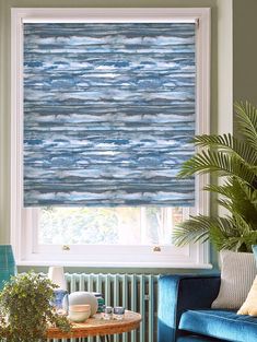 a living room with blue couches and a window covered in roman blind coverings