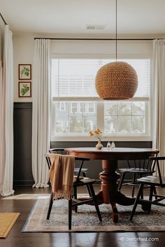 a dining room table with four chairs and a round light fixture hanging from the ceiling