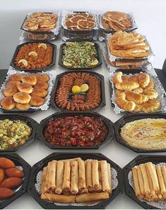 a table topped with lots of trays filled with different types of foods and pastries