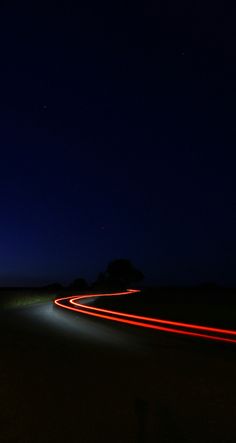 car lights streaking through the night sky on a road in the middle of nowhere