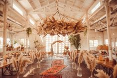 a room filled with lots of tables and chairs covered in pamodian feathers hanging from the ceiling