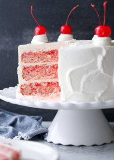 a slice of cake with white frosting and cherries on top