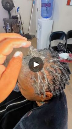 a man with dreadlocks is cutting another mans hair