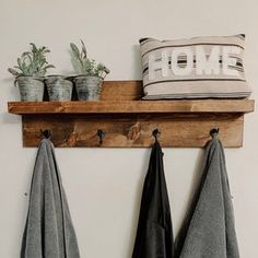 two towels hanging on a wooden shelf with potted plants