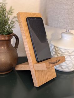 a cell phone in a wooden stand next to a potted plant on a table