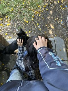 a person holding a cell phone up to their ear while standing next to a black cat