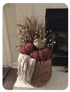 a basket filled with balls of yarn sitting on top of a floor next to a fireplace