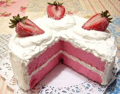 a strawberry cake with white frosting and two strawberries on top, sitting on a doily