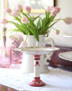 pink tulips are in vases on a table with white linen and plates