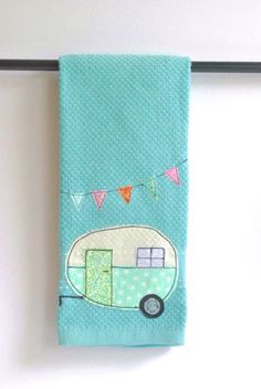 a teal towel with a camper on it hanging from a metal bar in front of a white wall