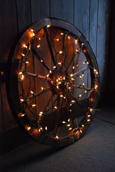 a ferris wheel with lights on it sitting in front of a wooden wall