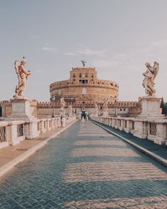 an old bridge with statues on it and a building in the background that has roman architecture