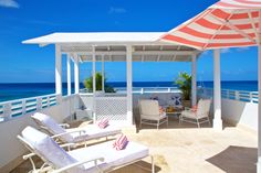 an umbrella and chairs are on the balcony overlooking the ocean