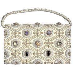 This vintage ornately embroidered and decorated clutch styled evening handbag was made in India in approximately 1940 in the period Anglo-Indian style. The outer shell of the purse is constructed of a heavy cotton with has been intricately embroidered with a combination of gold and silver toned wire and accented with inset cabachon polished stones. The earth tones of the cotton exterior are accented with silk lining and compartments, and is secured with a large snap clasp. The purse is labelled Luxury Vintage Satchel Evening Bag, Luxury Vintage Embellished Evening Bag, Luxury Traditional Handheld Shoulder Bag, Luxury Antique Gold Bags, Luxury Antique Style Party Bags, Luxury Beaded Traditional Clutch, Luxury Traditional Beaded Clutch, Luxury Antique Style Evening Bag For Parties, Luxury Vintage Party Bag