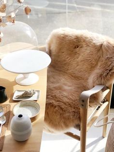 a dog sitting in a chair next to a table with plates and cups on it