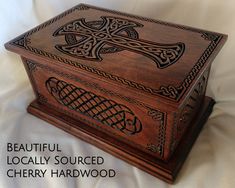 a wooden box with intricate carvings on the lid and sides, sitting on a white sheet