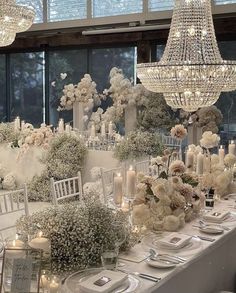 a table set up with white flowers and candles