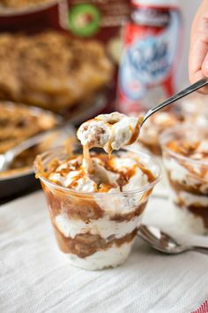 a person is spooning some food out of a glass bowl with ice cream and caramel on top