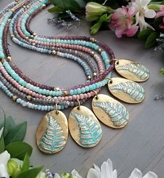 "This luxe, beaded necklace features one of two beautiful, 24kt gold-plated leaf pendants. The textured fern leaf and alder leaf designs are then hand-painted to achieve a lovely, turquoise patina look. The necklace is fully beaded with a gradient of shimmery, gray Labradorite gemstones, faceted brass, and shimmery, blue and silver Czech glass beads. The pedant measures approximately 1.25\" long x .625-.875\" wide and the beaded necklace measures 18\" with the option to add a 2\" extender. The n Artisan Gold Beaded Necklaces With Gemstone Beads, Nature-inspired Gold Beaded Jewelry, Bohemian Gold Bead Necklaces With Oval Beads, Nature-inspired Gold Jewelry With Gemstone Beads, Nature-inspired Gold Jewelry With Round Beads, Bohemian Necklace With Oval Gold Beads, Adjustable Beaded Labradorite Necklaces, Gold Labradorite Jewelry With Faceted Beads, Nature-inspired Hand Wrapped Labradorite Necklace