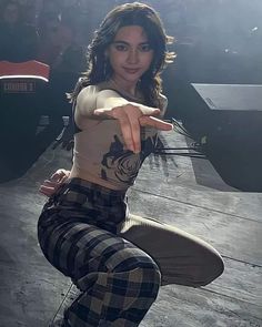 a woman in plaid pants pointing at the camera