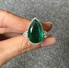 A one-of-a-kind, classic 9.37 carat Zambian Emerald center stone, with 0.62 carat of pear-shaped Diamonds and 0.22 carat of round cut Diamonds around it, all set in 18K solid White Gold. The Emerald is transparent, lustrous and of an ideal vivid green color, making it a very eye-catching engagement or cocktail ring. 18K White Gold: 6.34 Grams  Emerald pear shaped: 9.37 Ctw (1200 )  Diamond Pear Shape: 0.62 Ctw Diamond Round: 0.22 Ctw Luxury Pear-shaped Emerald Ring For Formal Occasions, Gia Certified Teardrop Diamond Ring For Formal Occasions, Formal Gia Certified Teardrop Diamond Ring, Luxury Pear-shaped Brilliant Cut Emerald Ring, Formal Pear-shaped Emerald Ring In White Gold, Luxury Teardrop Emerald Ring As Gift, Teardrop Emerald Ring For Formal Occasions, Luxury Teardrop Emerald Ring For Gift, Luxury Pear-shaped Emerald Ring With Prong Setting