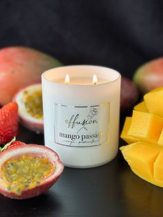 a white candle sitting on top of a table next to sliced mangoes and strawberries