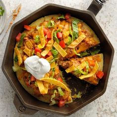 a skillet filled with taco salad and sour cream