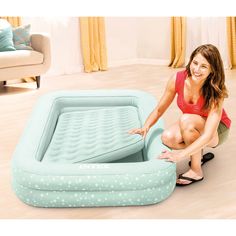 a woman sitting on the floor next to an inflatable bed with a mattress