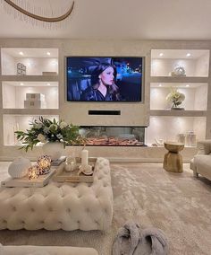 a living room filled with furniture and a flat screen tv mounted on the wall above a fireplace