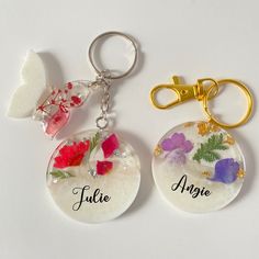 two key chains with flowers on them and the words future, angel, and nature